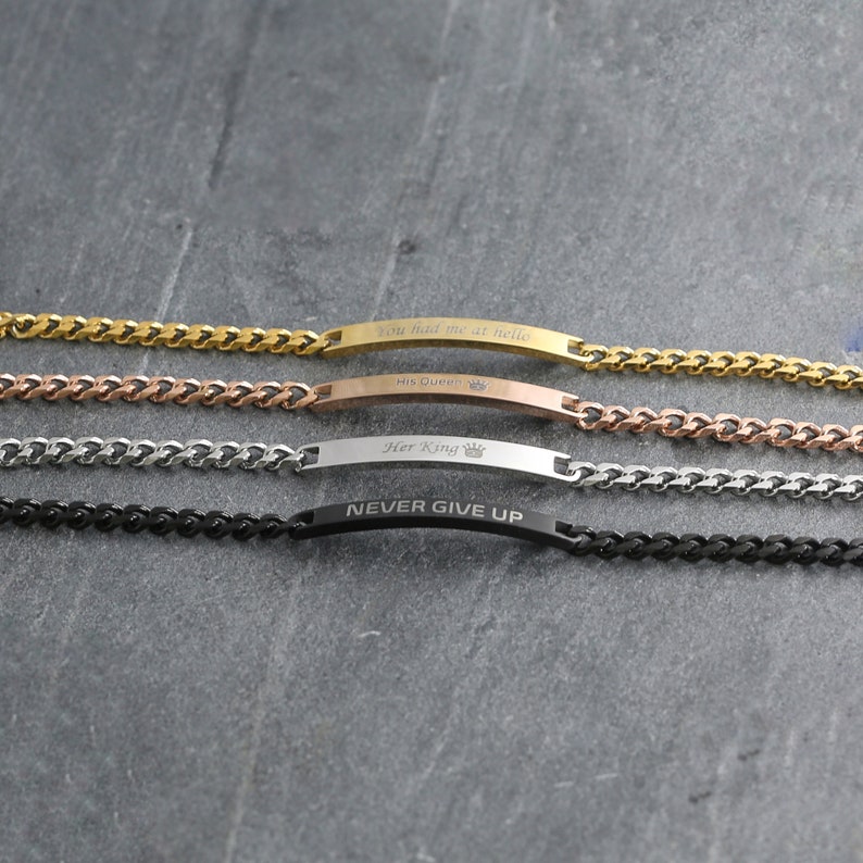 May include: Four bracelets with curb chains and rectangular nameplates. The bracelets are gold, rose gold, silver, and black. The nameplates are engraved with the phrases "You had me at hello", "His Queen", "Her King", and "NEVER GIVE UP".