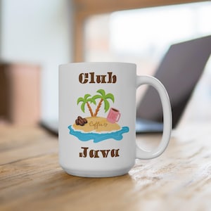 Peut inclure: Mug à café en céramique blanche avec les mots "Club Java" en lettres marron. La tasse présente un graphisme coloré d'île avec des palmiers, des grains de café et une tasse à café rose. La tasse est sur une surface en bois.