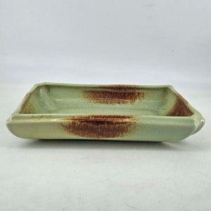 May include: A rectangular ceramic tray with a light green glaze and brown splotches. The tray has a slightly raised rim.