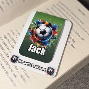 May include: A green magnetic bookmark with a colorful soccer ball graphic and the name "Jack" printed in white. The bookmark is designed for book lovers who enjoy sports.