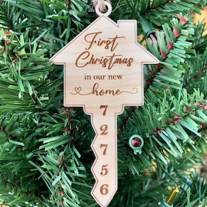May include: Wooden Christmas ornament shaped like a house key with the text "First Christmas in our new home" and the numbers 72756 on the key.