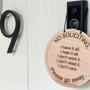 K&ouml;nnte beinhalten: Ein rundes Schild aus Holz mit dem Text "NO SOLICITING" und der Nachricht "I have it all. I hate it all. I don't want it. I don't need it. I don't care. Please go away."
