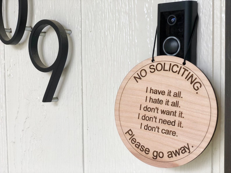K&ouml;nnte beinhalten: Ein rundes Schild aus Holz mit dem Text "NO SOLICITING" und der Nachricht "I have it all. I hate it all. I don't want it. I don't need it. I don't care. Please go away."