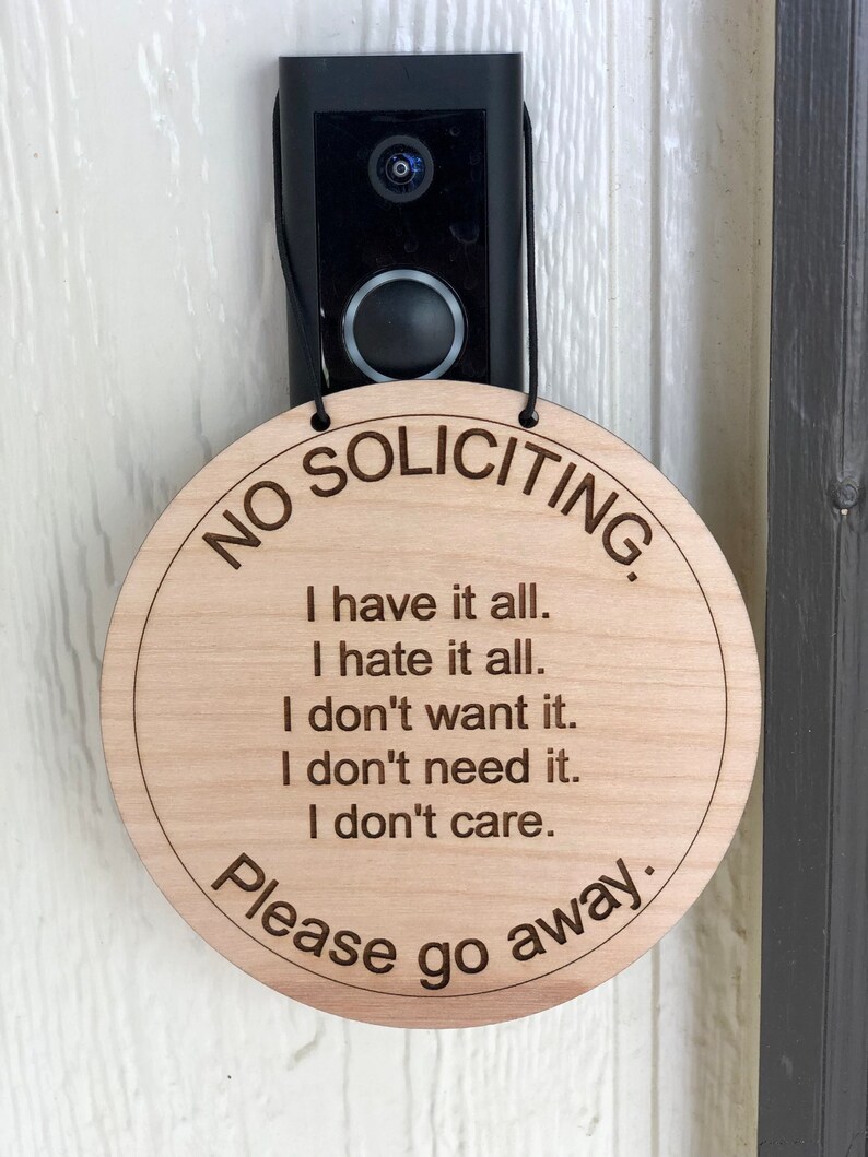 K&ouml;nnte beinhalten: Ein rundes Schild aus Holz mit dem Text "NO SOLICITING" in einem Kreis um den Rand. Das Schild hat auch den Text "I have it all. I hate it all. I don't want it. I don't need it. I don't care. Please go away." in der Mitte.