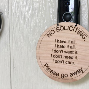 K&ouml;nnte beinhalten: Ein rundes Schild aus Holz mit dem Text "NO SOLICITING." und der Nachricht "I have it all. I hate it all. I don't want it. I don't need it. I don't care. Please go away."