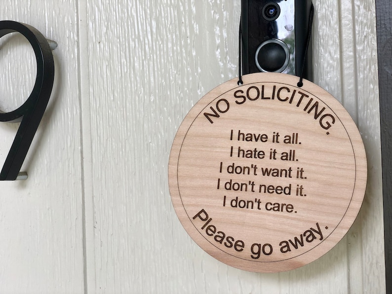 K&ouml;nnte beinhalten: Ein rundes Schild aus Holz mit dem Text "NO SOLICITING." und der Nachricht "I have it all. I hate it all. I don't want it. I don't need it. I don't care. Please go away."