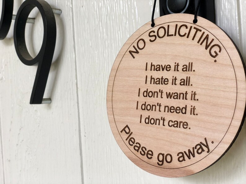 K&ouml;nnte beinhalten: Ein rundes Schild aus Holz mit dem Text "NO SOLICITING" in einem Kreis um den Rand. Das Schild enth&auml;lt auch den Text "I have it all. I hate it all. I don't want it. I don't need it. I don't care. Please go away."