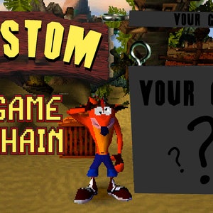 May include: Custom PlayStation 1 game keychain with a black and gray game cartridge. The cartridge has the text "YOUR GAME" and question marks. The keychain is next to a cartoon character from the Crash Bandicoot video game series.
