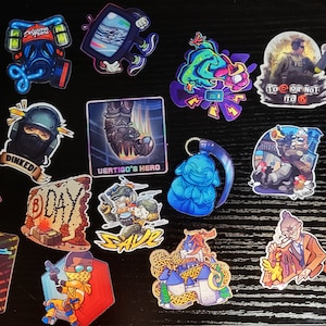 May include: A collection of colorful stickers featuring various designs related to the video game Counter-Strike: Global Offensive. The stickers include characters, weapons, and logos from the game. Some of the stickers have text, such as "Dinked!" and "CS on the GO".