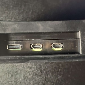Op de afbeelding: Een zwart rechthoekig apparaat met drie USB-poorten aan de zijkant.