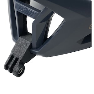 May include: A close-up of a black helmet with a GoPro mount attached to the bottom. The helmet has a textured surface and the brand name "LEATT" is visible on the side.