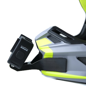 May include: A black GoPro camera mounted on a grey and yellow helmet with a black strap. The camera has a black button and the GoPro logo is visible.