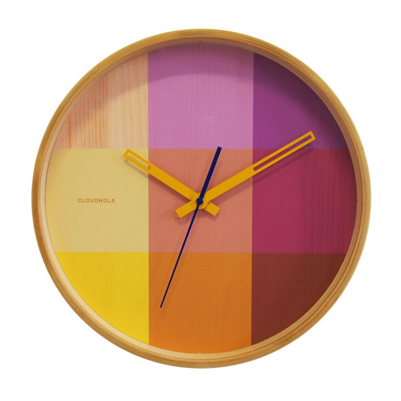 This trendy 30 cm wooden wall clock has a vibrant printed clock face with the pattern of colorful squares in a mix of yellow & magenta. The silent clock is finished with a oker yellow hour and minute hand and a smooth moving dark blue second hand.