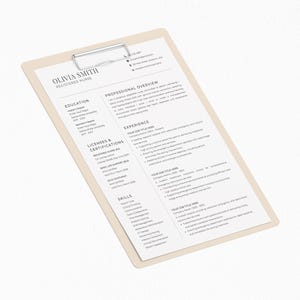 May include: A beige clipboard with a silver clip holding a resume. The resume is white with black text, including the name "OLIVIA SMITH REGISTERED NURSE". The clipboard is angled, with the text clearly visible.