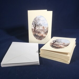 May include: A stack of blank greeting cards with white envelopes. The cards feature a watercolor painting of a tree and a field in an oval frame. The text "J.E. Smith" is printed in the bottom right corner of the cards.