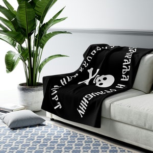 May include: Black fleece throw blanket with a white skull and crossbones design and the text "The only thing we have to fear is fear itself" in Russian.