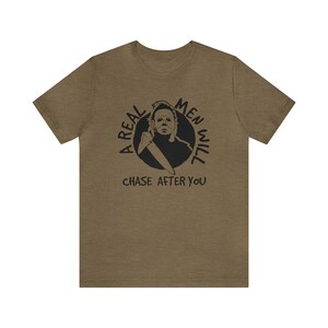 May include: A green t-shirt with a black graphic of a man with a knife and the text "A real men will chase after you".