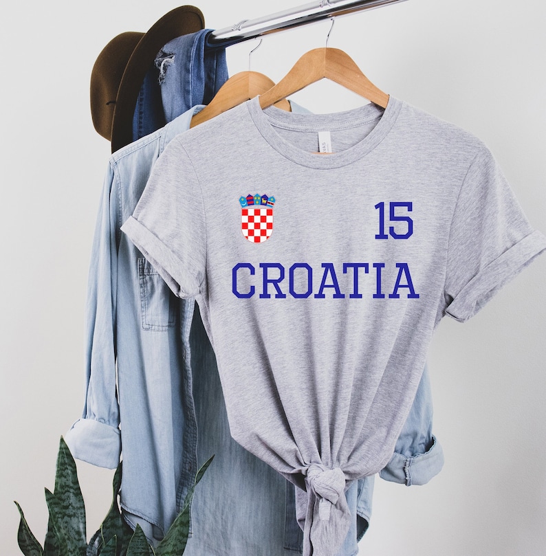 May include: Gray t-shirt with a blue and red Croatian crest and the text "CROATIA" and the number "15" printed on it.