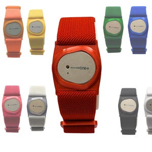 May include: A collection of Dexcom One+ continuous glucose monitors in various colors, including red, yellow, pink, green, blue, and gray. Each device features a central display and a fabric strap for wearing on the wrist.