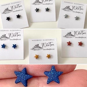 May include: A set of six pairs of star-shaped earrings in various colours, including black, grey, blue, brown, and gold. The earrings are handmade in Cornwall, England.