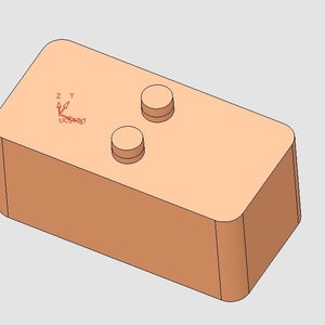 Pode incluir: Um bloco retangular de cor castanho claro com dois botões redondos castanhos no topo. O bloco tem um rótulo vermelho com o texto "UCS#001" e setas que indicam os eixos x, y e z.