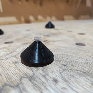 May include: Five black plastic cones with a white ring on top, arranged on a wooden surface.