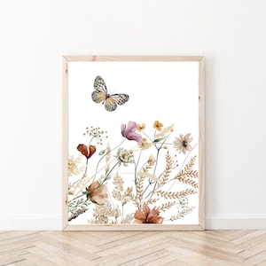 May include: A watercolor painting of a butterfly flying over a bouquet of wildflowers in shades of brown, pink, and yellow. The flowers are arranged in a cluster, with the butterfly flying above them. The background is white.