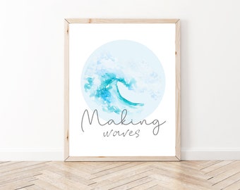 May include: A framed art print featuring a watercolor illustration of a wave in shades of blue and teal, set against a light blue circle. The words "Making waves" are written in a cursive font below the wave image. The frame is made of light-colored wood.