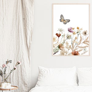 May include: A framed print featuring a watercolor illustration of a butterfly flying over a bouquet of dried flowers in shades of brown, pink, and white.