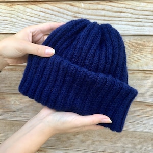 May include: A dark blue knitted beanie hat with a ribbed texture.