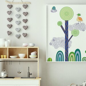 May include: A white framed print of a stylized tree with blue, green, and orange details. The tree has a bird perched on a branch. The print is hanging on a white wall above a wooden shelf with dishes and cups.