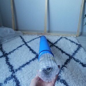 Pu&ograve; includere: Un dipinto su tela arrotolato in un tubo protettivo blu con bolle d'aria. Il tubo &egrave; tenuto da una mano.