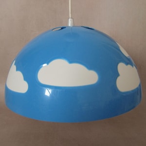 May include: A blue pendant light fixture with white cloud designs. The light has a rounded, dome-like shape and is suspended by a white cord. The fixture is designed with a sky and cloud theme.