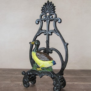 Peut inclure: Un écran de cheminée décoratif en métal noir sur le thème du canard. La figurine de canard est de couleur jaune, marron et bleu. L'écran a un design orné et défilé et est soutenu par quatre petits pieds.