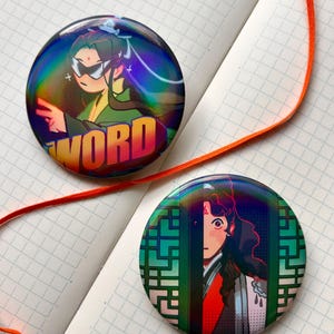 以下が含まれることがあります： アニメスタイルのイラストが描かれた、丸いホログラフィックバッジが2つ。1つはサングラスをかけたキャラクターと「WORD」の文字。もう1つは、緑色の幾何学模様の背景にキャラクターが描かれています。