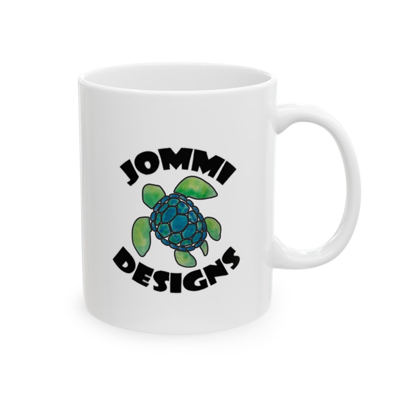 May include: White ceramic mug with a black and green logo that says "JOMMI DESIGNS" and features a blue and green sea turtle.