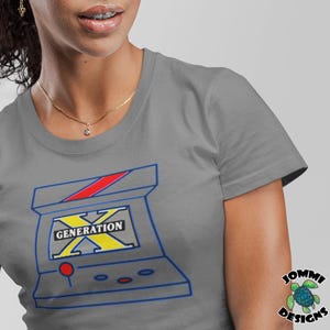 May include: Gray t-shirt with a retro video game design. The game is called "Generation X" and features a red, blue, and yellow color scheme.