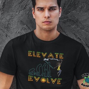 May include: Black t-shirt with the words "ELEVATE EVOLVE" in orange and green tribal-style lettering. The shirt features an illustration of human evolution, culminating in a dancing figure. A logo with a turtle is on the right sleeve.
