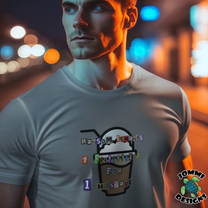 Pode incluir: Uma camiseta branca com um gráfico de uma xícara de café com o texto "Ransom Demands 1 Frappuccino For 1 Hostage". O texto é composto por letras coloridas recortadas de revistas.