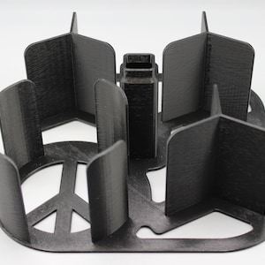May include: Black 3D-printed organizer with a peace sign cutout. The organizer has multiple compartments and a central section. The design features curved dividers and a rectangular base. The overall shape is geometric and functional.