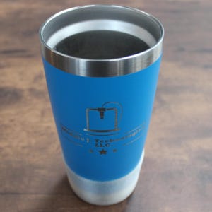 May include: A blue insulated tumbler with a silver rim and base. The tumbler features a logo with the text "Midwest Technologies LLC" and a 3D printer graphic. The tumbler is designed to keep beverages cold or hot.