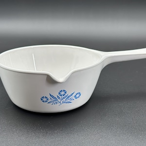 May include: White ceramic saucepan with a blue floral design. The saucepan has a pouring spout and a handle.
