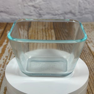 Peut inclure: Un plat carré en verre transparent avec un bord bleu clair. Le plat est vide et posé sur une surface blanche.