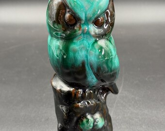 May include: A ceramic owl figurine with a glossy, mottled teal and brown glaze. The owl is perched on a tree stump base, with detailed features including large eyes and textured feathers. The figurine is approximately 4 inches tall.