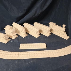 May include: A collection of unpainted plaster train set pieces, including a locomotive, train cars, and curved and straight track sections. The pieces are arranged on a dark blue surface, ready for painting and assembly.