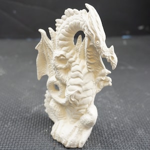 May include: White ceramic dragon figurine with wings outstretched, standing on a base. The dragon has a detailed, textured surface and a fierce expression.