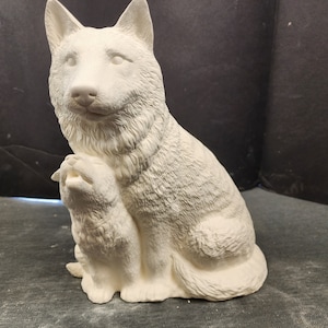 May include: White ceramic figurine of a dog sitting with a smaller dog in its lap. Both dogs have a furry texture.