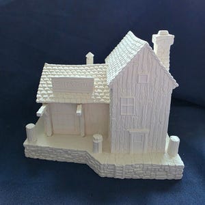 May include: A detailed, off-white miniature Bait & Tackle shop. The model features a textured roof, siding, and chimney. The shop has a small door, windows, and a sign that reads "Bait & Tackle". The base is made to look like stone.