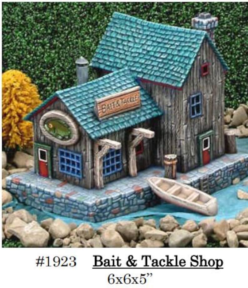 May include: A miniature Bait & Tackle Shop with a weathered wood appearance, teal roof, and stone foundation. Features a sign, a boat, and a fish emblem. Dimensions are 6x6x5 inches.