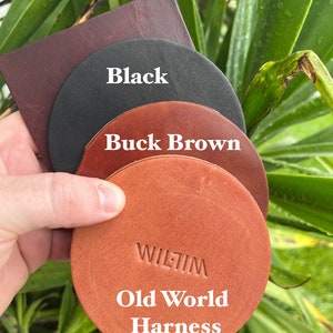May include: A selection of leather samples in shades of brown and black. The samples include a dark burgundy square, a black circle, a buck brown circle, and an old world harness circle with the text "WILTIM" and "Old World Harness".